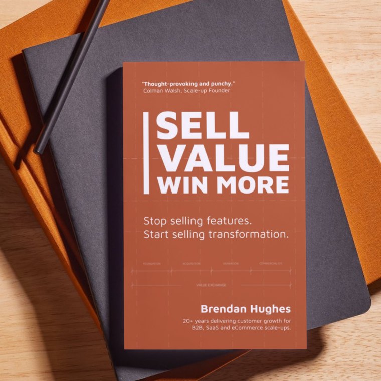 Sell Value. Win More. by Brendan Hughes, a terracotta paperback resting on a stack of notebooks. The cover reads: stop selling features, start selling transformation.